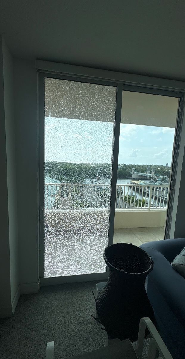 Cracked impact glass still held in a sliding glass door frame