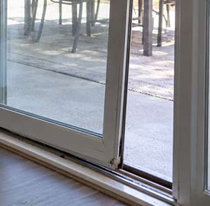 Close-up of a sliding glass door panel tilted off its bottom track